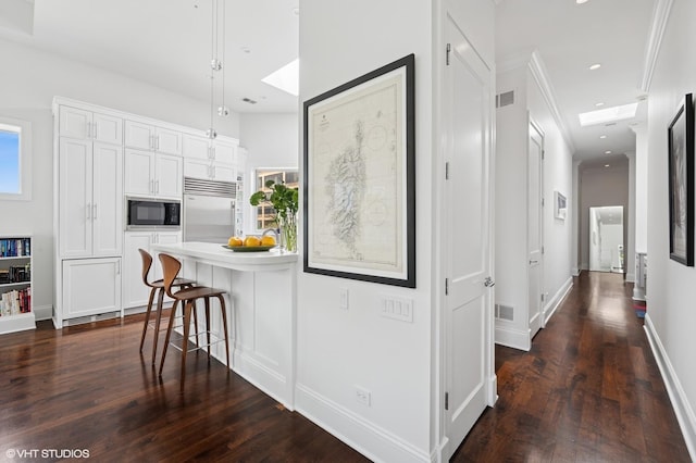 kitchen with built in appliances, a breakfast bar, dark wood-style flooring, white cabinets, and recessed lighting