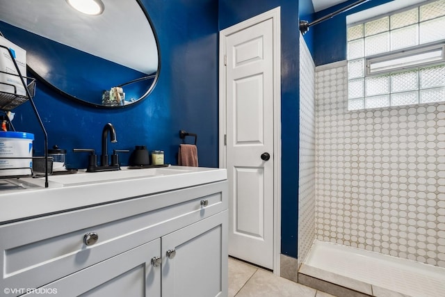 bathroom featuring a tile shower, tile patterned flooring, and vanity