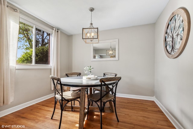 dining room with baseboards, wood finished floors, and a chandelier