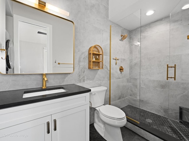 bathroom with a stall shower, tile walls, vanity, and toilet