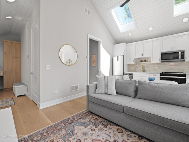 living room featuring a skylight, light wood finished floors, wooden ceiling, recessed lighting, and baseboards