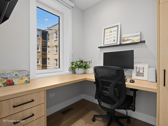 office area featuring built in study area, dark wood finished floors, and baseboards