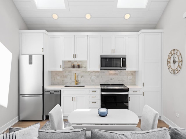 kitchen featuring appliances with stainless steel finishes, a sink, recessed lighting, backsplash, and white cabinets