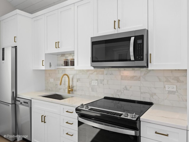 kitchen featuring stainless steel appliances, a sink, open shelves, and white cabinetry