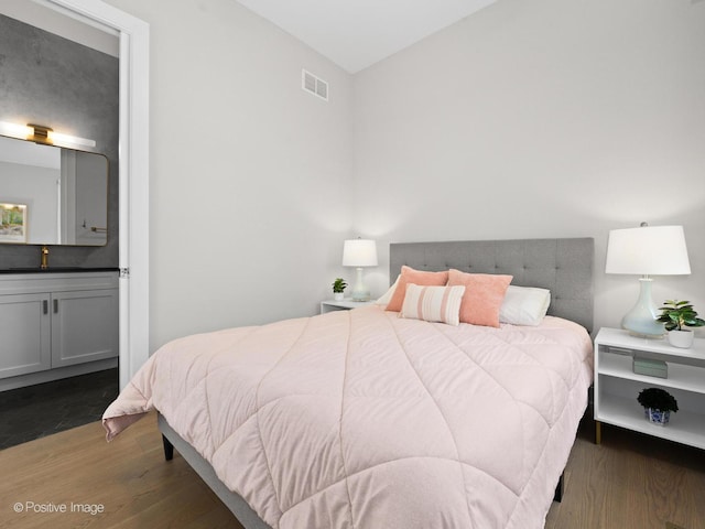 bedroom with a sink, wood finished floors, and ensuite bath
