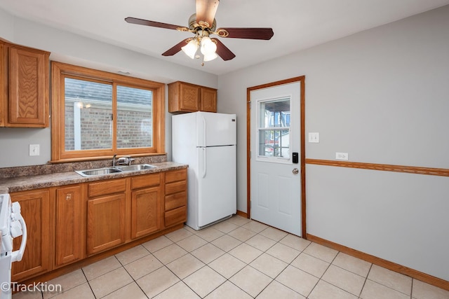 kitchen featuring freestanding refrigerator, a sink, brown cabinets, and healthy amount of natural light