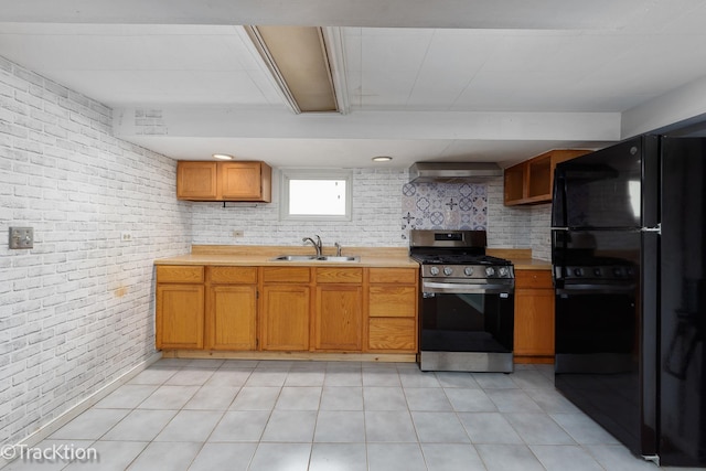 kitchen with freestanding refrigerator, stainless steel gas range, a sink, wall chimney range hood, and light countertops