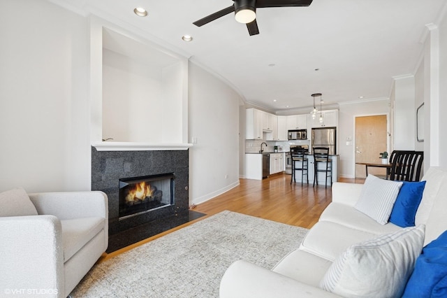 2700 N Halsted St Unit 406, Chicago, IL 60614 - living area featuring light wood-style floors, a ceiling fan, a fireplace with flush hearth, recessed lighting, and ornamental molding