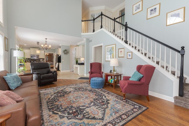6 Conway Cir, Bloomington, IL 61704 - living room featuring a chandelier, light wood-style floors, stairway, a high ceiling, and baseboards