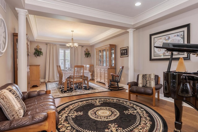 6 Conway Cir, Bloomington, IL 61704 - living room featuring decorative columns, wood finished floors, a tray ceiling, a chandelier, and crown molding