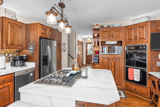 1723 Columbine Dr, Schaumburg, IL 60173 - kitchen featuring appliances with stainless steel finishes, brown cabinets, a kitchen island, light stone counters, and wood finished floors
