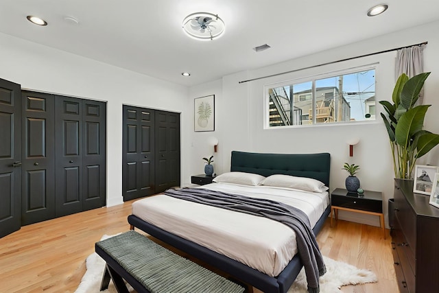 bedroom featuring two closets, light wood-style flooring, and recessed lighting