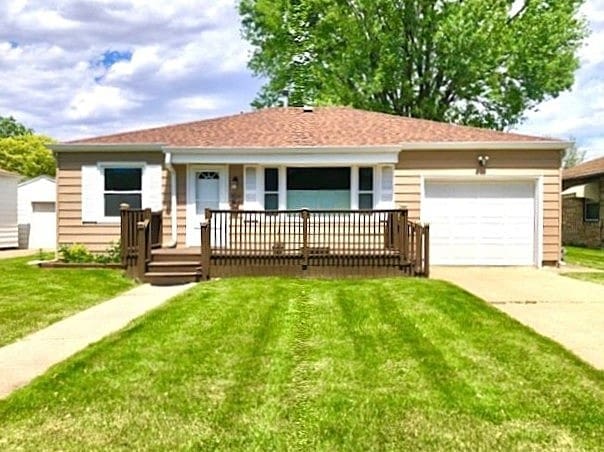 ranch-style home featuring covered porch, an attached garage, driveway, and a front lawn
