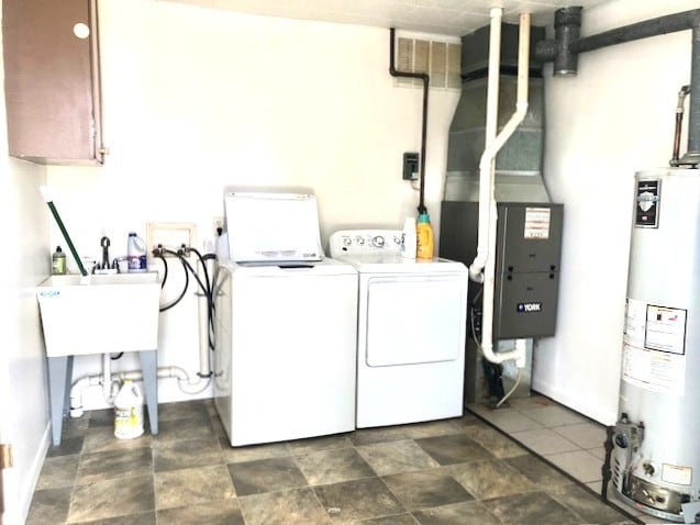 laundry area featuring water heater, independent washer and dryer, baseboards, and cabinet space