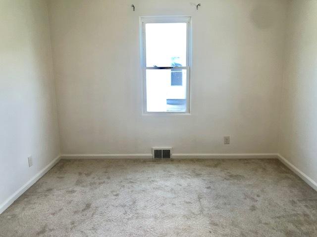 empty room featuring light carpet and baseboards