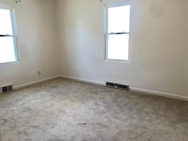 empty room featuring carpet floors, plenty of natural light, and baseboards