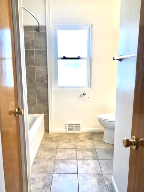 full bath with toilet, tile patterned flooring, shower / bathtub combination, and baseboards