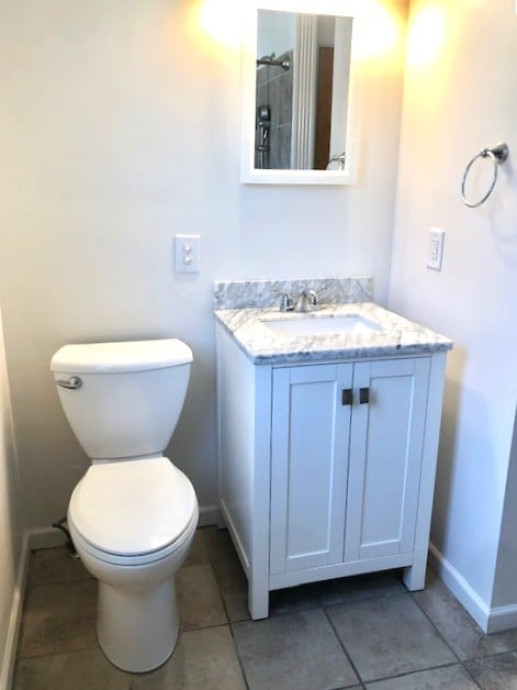 bathroom with baseboards, vanity, tile patterned flooring, and toilet