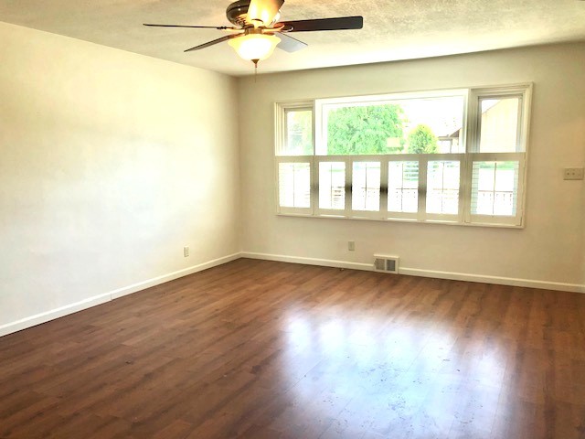 spare room featuring ceiling fan, baseboards, and dark wood-style flooring