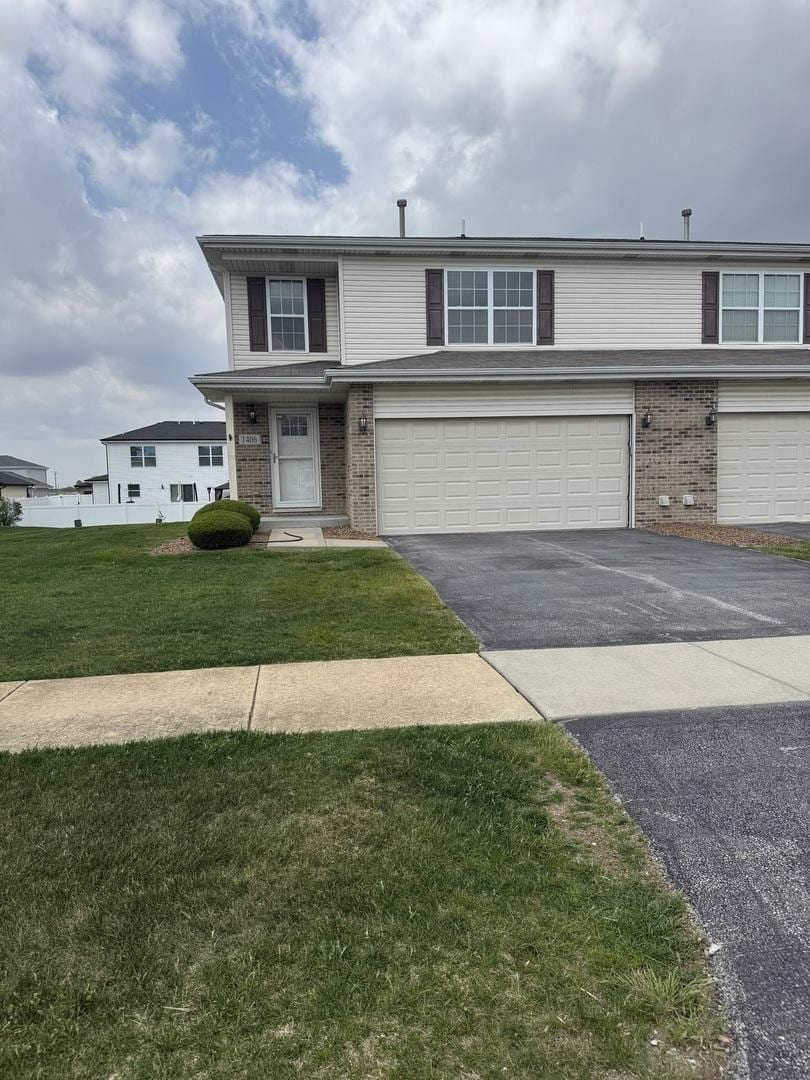view of front of property featuring driveway, an attached garage, a front yard, and brick siding