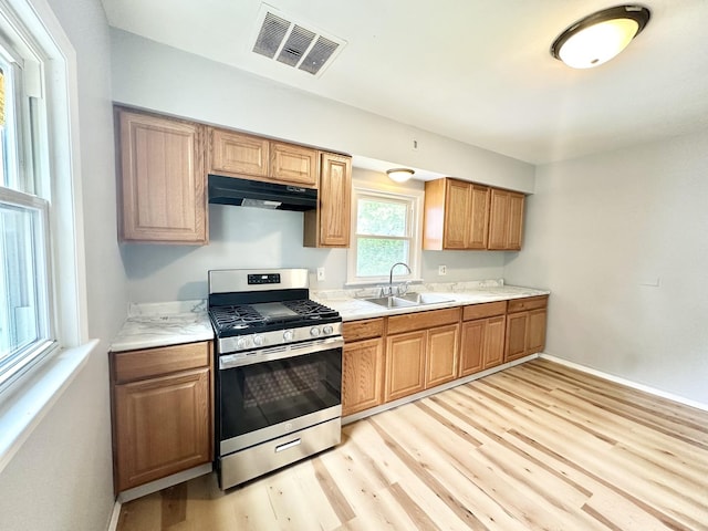 301 Illinois Ave, Elgin, IL 60120 - kitchen featuring stainless steel range with gas cooktop, a sink, under cabinet range hood, light wood finished floors, and light countertops