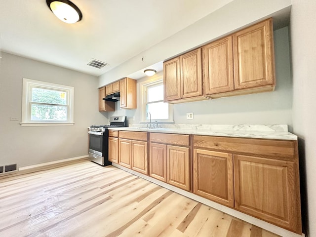 301 Illinois Ave, Elgin, IL 60120 - kitchen with stainless steel gas stove, under cabinet range hood, light wood-style flooring, and healthy amount of natural light