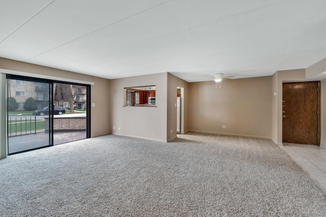 carpeted spare room featuring baseboards and ceiling fan