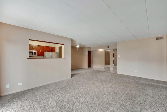 spare room featuring baseboards, light carpet, and ceiling fan