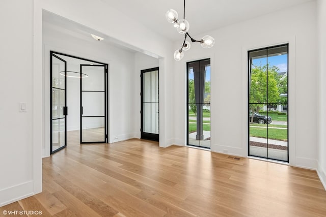 613 S Chatham Ave, Elmhurst, IL 60126 - unfurnished room with light wood-style flooring, a chandelier, and baseboards