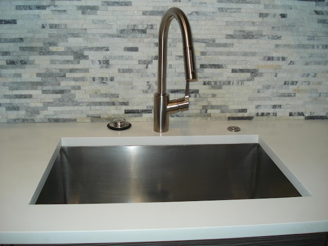 kitchen view of a sink, tasteful backsplash, and light countertops