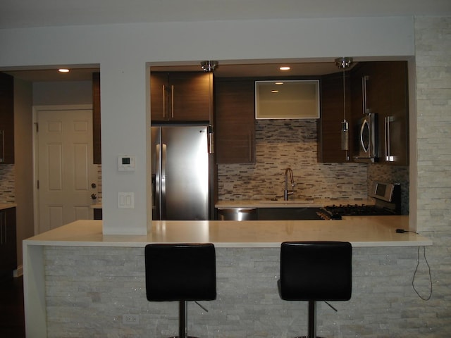 kitchen featuring appliances with stainless steel finishes, a sink, light countertops, decorative backsplash, and recessed lighting