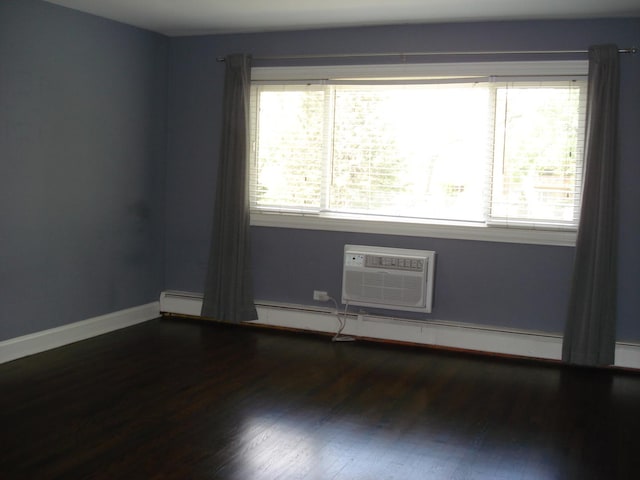 empty room featuring plenty of natural light, wood finished floors, a baseboard radiator, and an AC wall unit