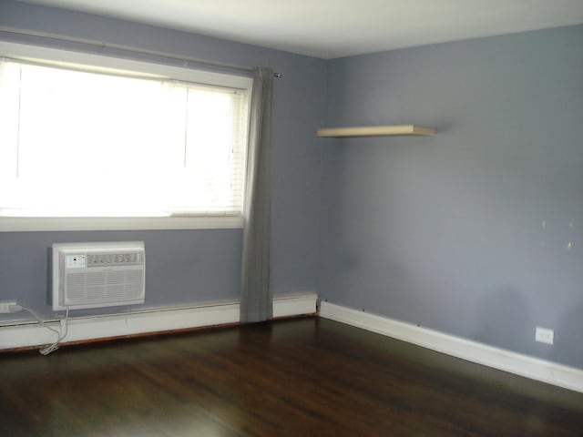empty room with wood finished floors, baseboards, an AC wall unit, and baseboard heating
