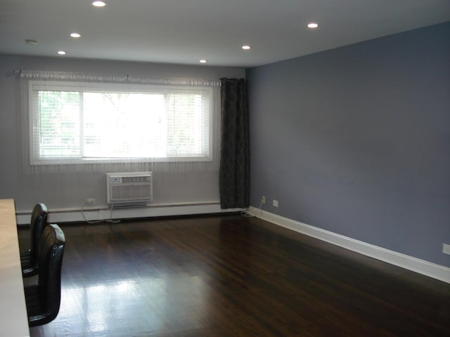 spare room featuring a wall mounted AC, recessed lighting, wood finished floors, baseboards, and a baseboard radiator
