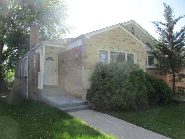 view of front facade with brick siding and a chimney