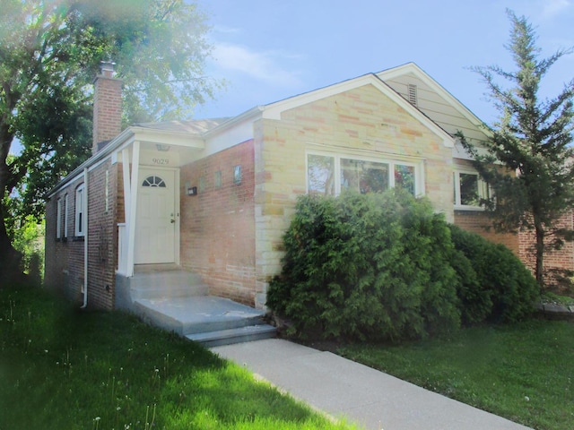 9029 S Crandon Ave, Chicago, IL 60617 - view of front of property featuring brick siding, a chimney, and a front yard