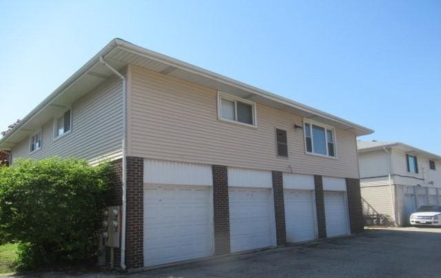 view of side of home with brick siding, driveway, and a garage