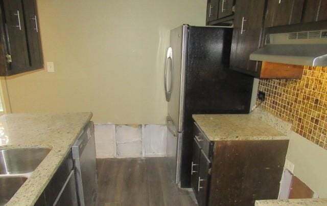 kitchen with under cabinet range hood, decorative backsplash, dark brown cabinetry, and dark wood finished floors