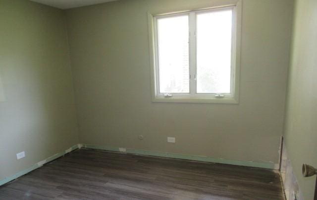 unfurnished room with plenty of natural light, dark wood-type flooring, and baseboards