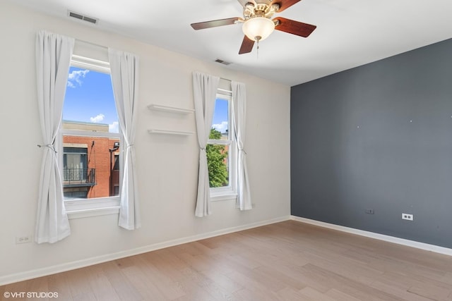 spare room with wood finished floors, ceiling fan, and baseboards