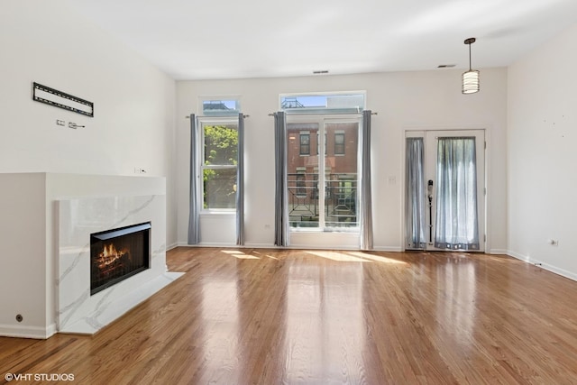 unfurnished living room with wood finished floors, a premium fireplace, and baseboards