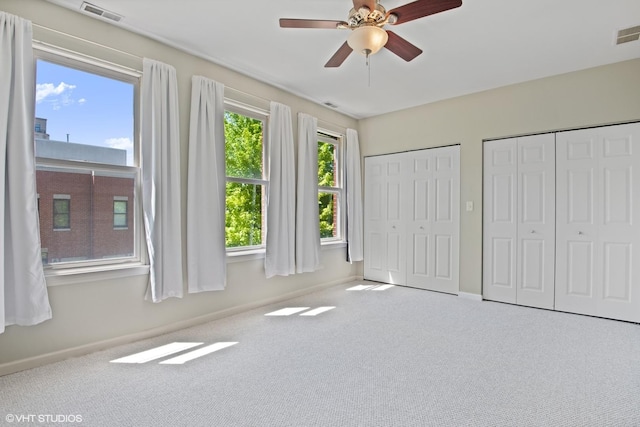 unfurnished bedroom featuring two closets, carpet floors, and baseboards