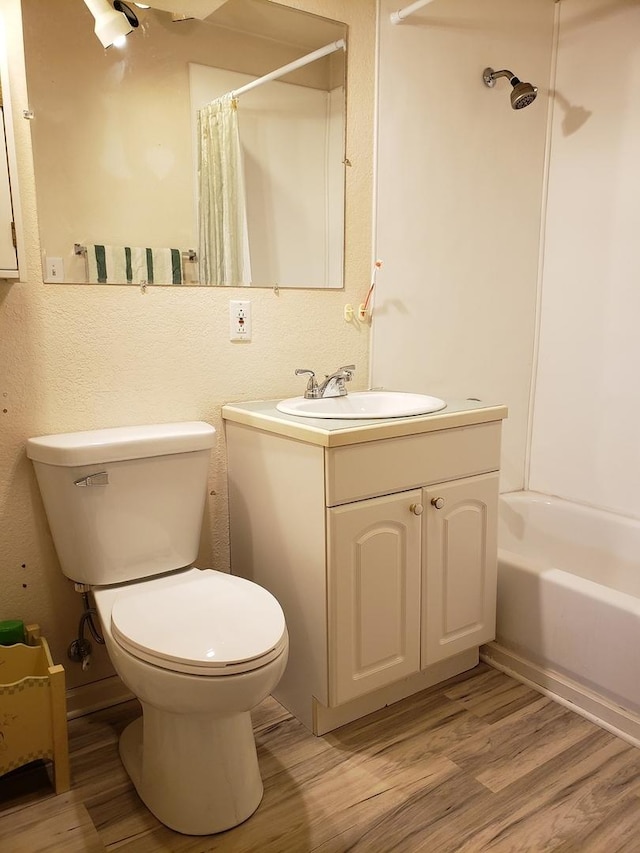 bathroom with wood finished floors, toilet, vanity, and shower / tub combo