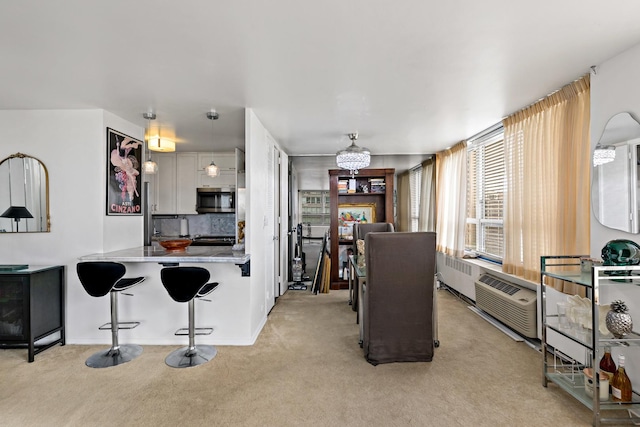 4800 S Chicago Beach Dr Unit 1106S, Chicago, IL 60615 - kitchen with stainless steel microwave, light carpet, a chandelier, a kitchen breakfast bar, and baseboards