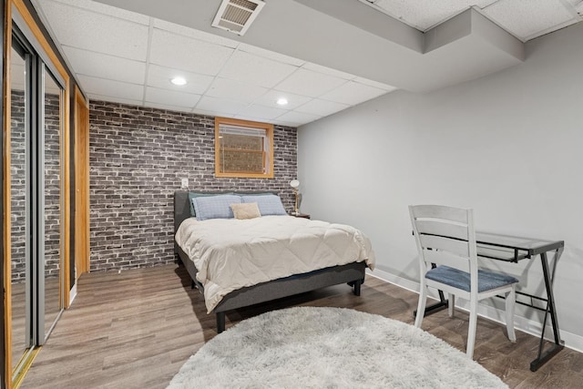 1235 Euclid Ave, Berwyn, IL 60402 - bedroom featuring brick wall, wood finished floors, a drop ceiling, baseboards, and recessed lighting