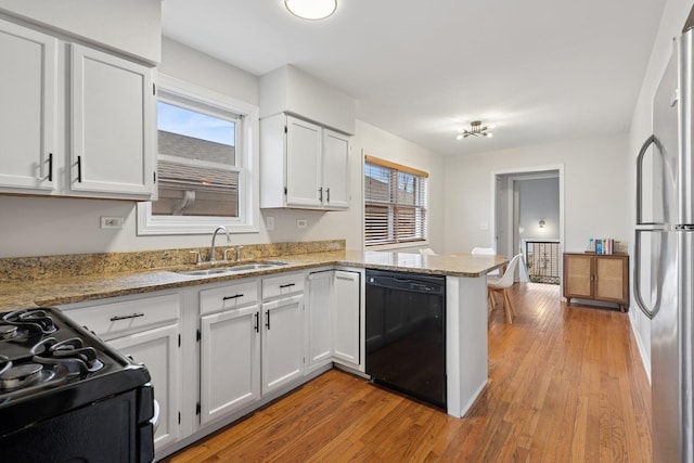 1235 Euclid Ave, Berwyn, IL 60402 - kitchen with black appliances, a sink, a peninsula, light wood finished floors, and white cabinetry