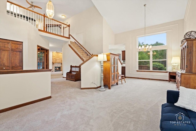 1748 Pinnacle Dr, Aurora, IL 60502 - carpeted living area featuring a chandelier, high vaulted ceiling, a stone fireplace, baseboards, and stairs