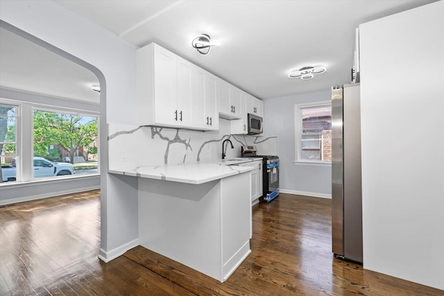 kitchen featuring appliances with stainless steel finishes, white cabinetry, dark wood-style floors, and a sink