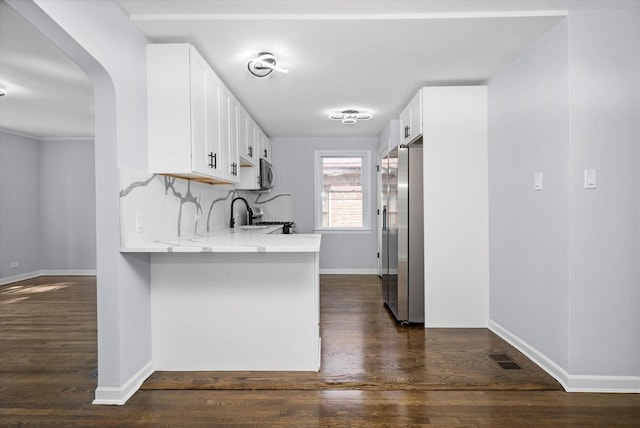 kitchen with stainless steel appliances, white cabinets, dark wood-type flooring, and a peninsula