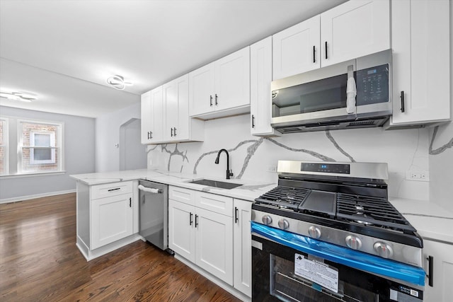 kitchen featuring appliances with stainless steel finishes, a sink, a peninsula, and white cabinetry